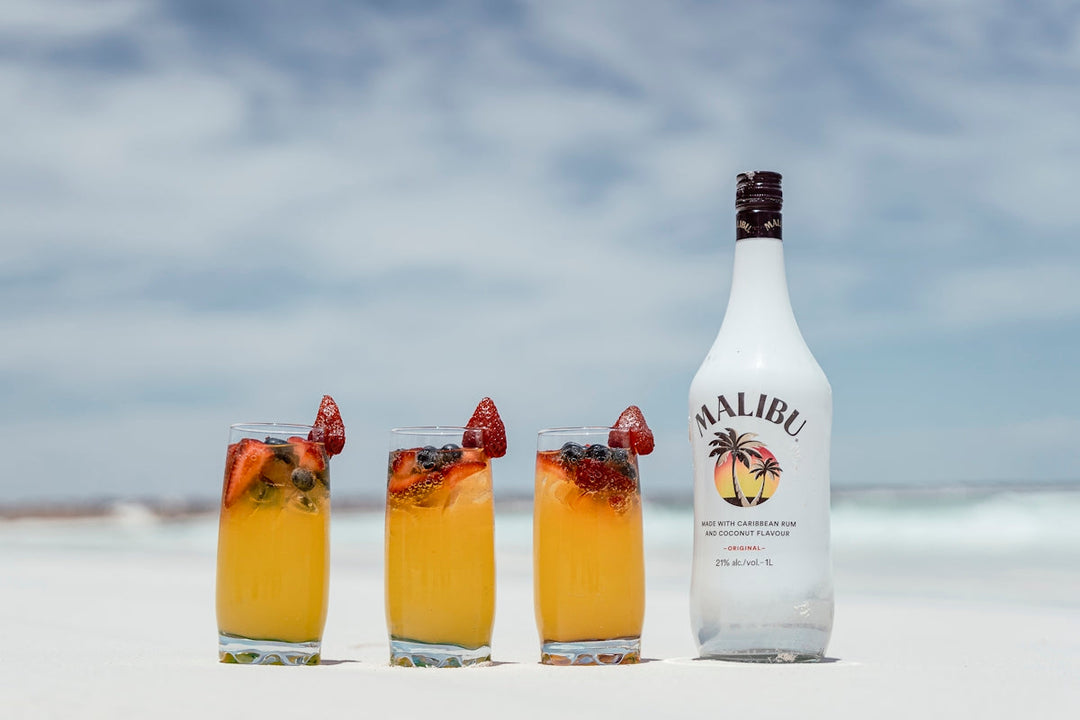 a bottle of alcohol next to three glasses filled with drinks