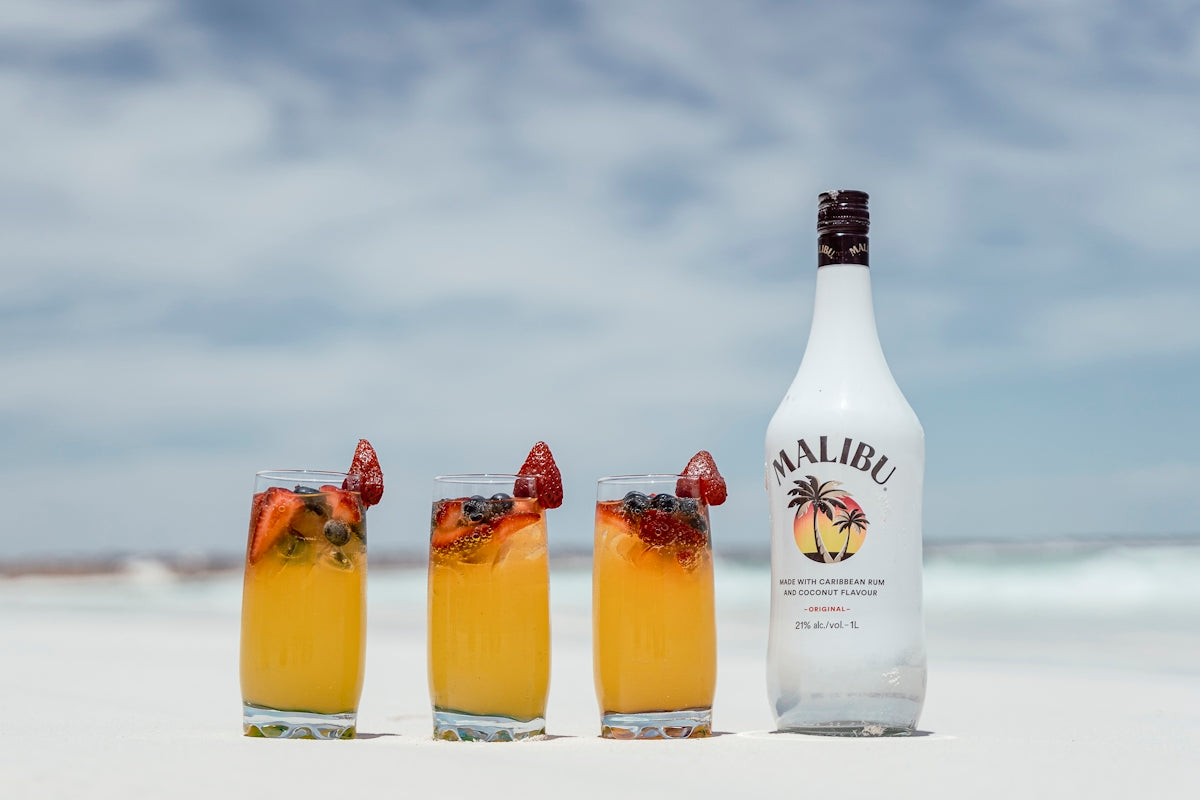 a bottle of alcohol next to three glasses filled with drinks