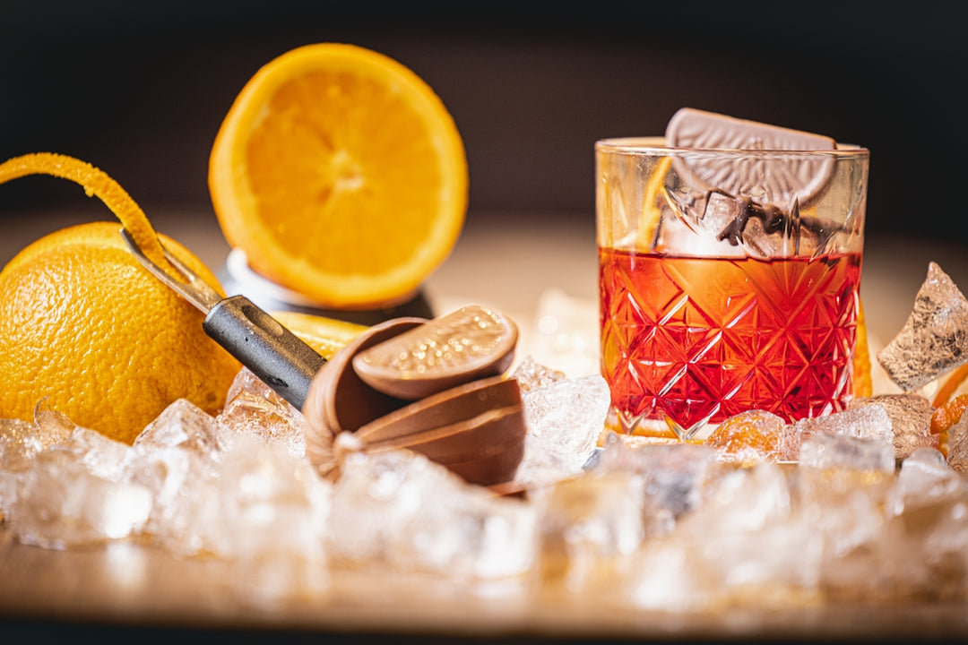 a glass of whiskey next to an orange