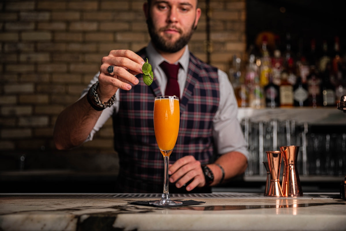 a man in a vest and tie holding a glass of orange juice