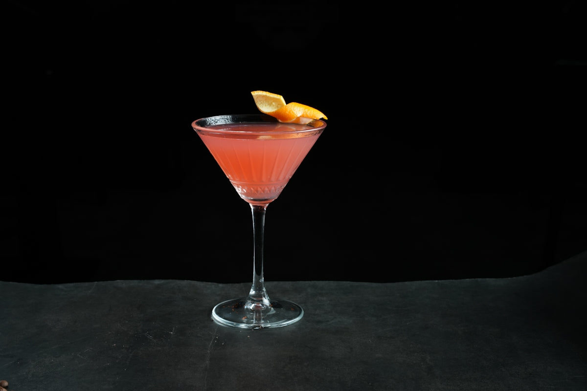 a pink drink with a slice of lemon on the rim