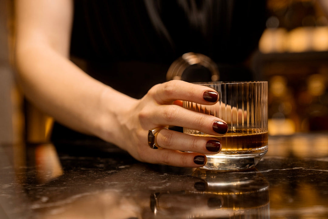 a woman's hand holding a glass of whiskey