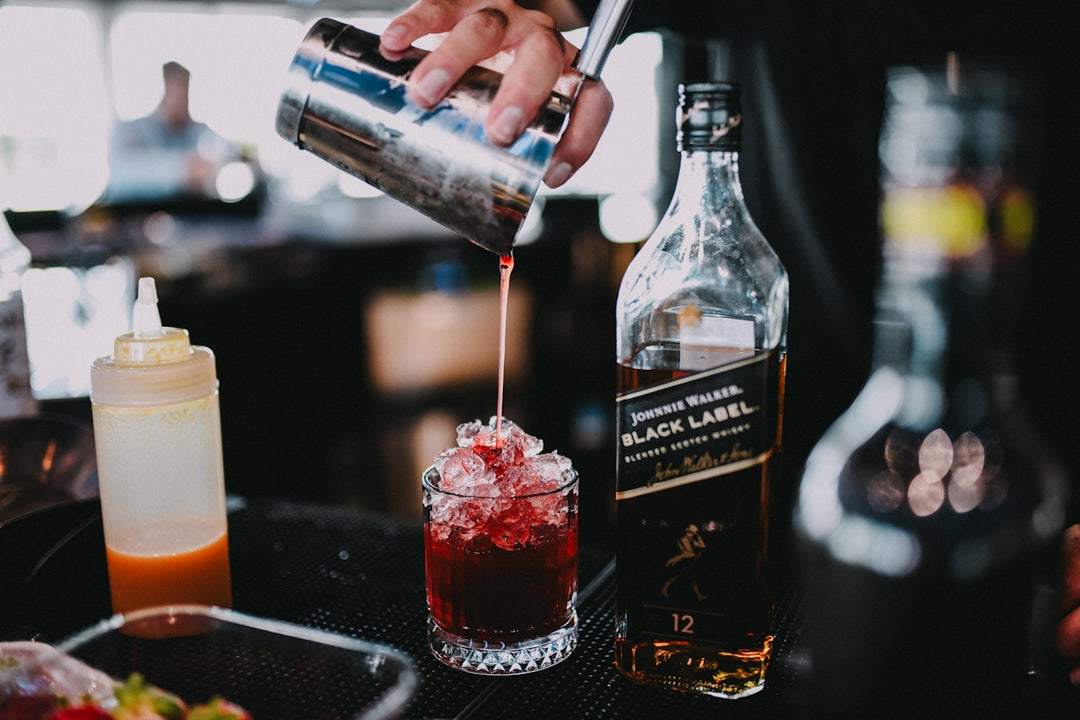a bartender pouring a cocktail into a glass