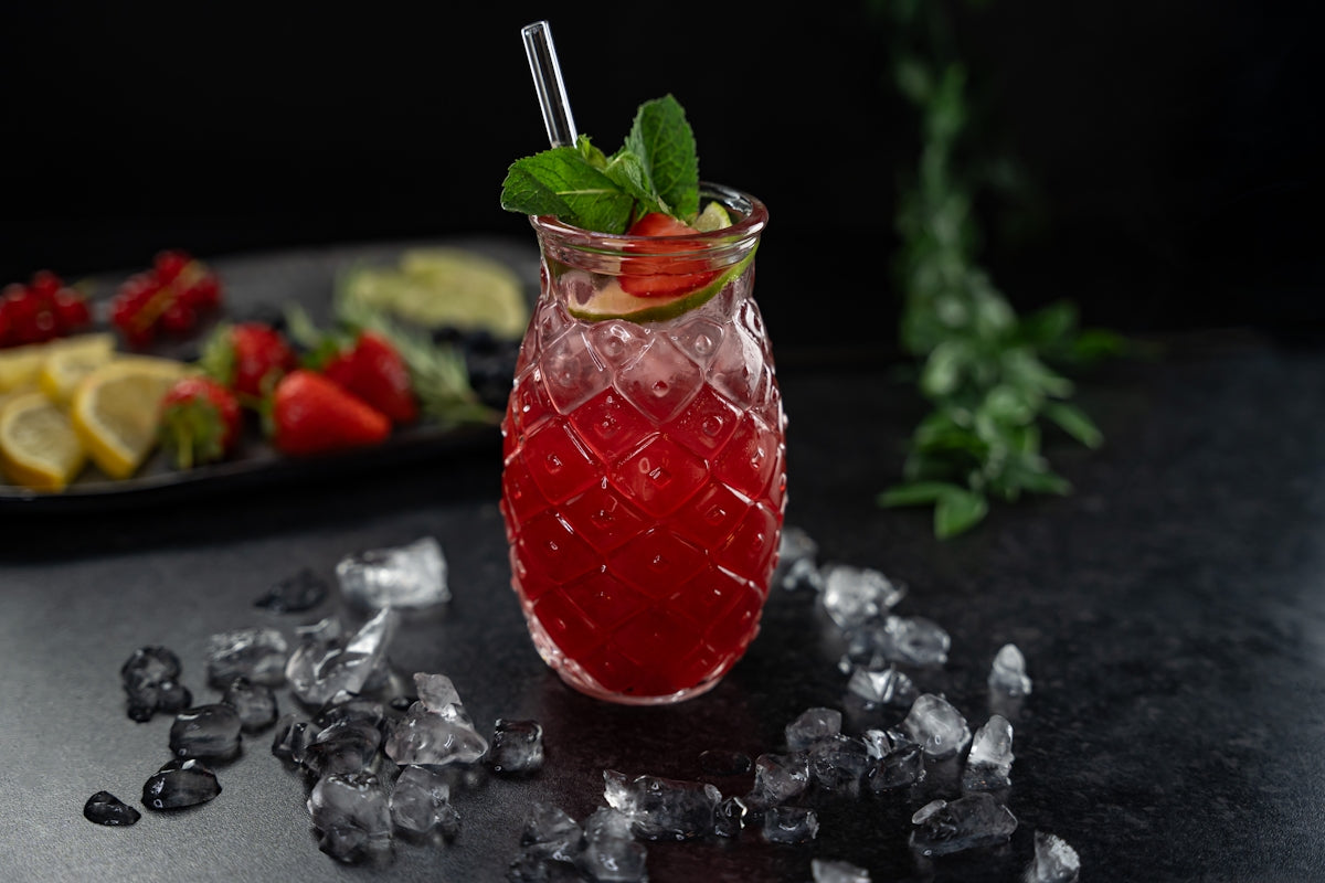 a glass filled with a drink next to a plate of fruit