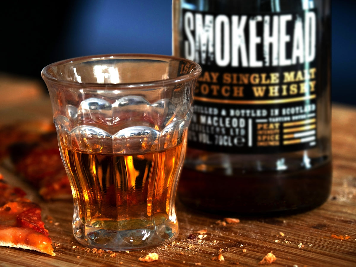 a glass of whiskey next to a bottle of alcohol