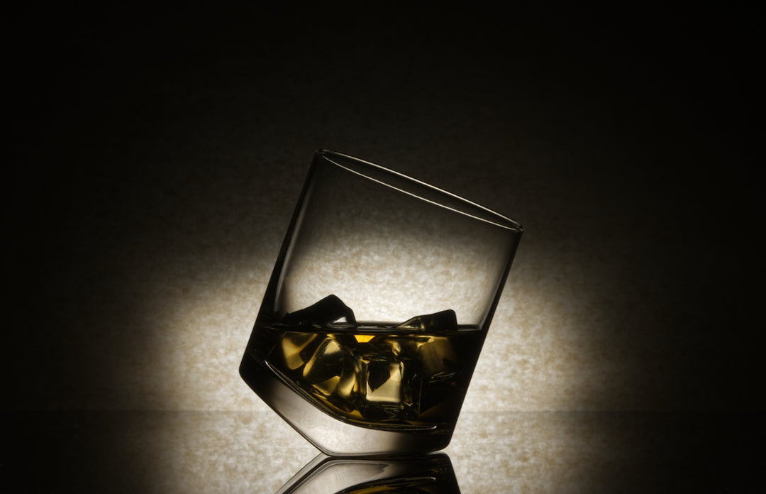 A glass of whiskey with ice cubes in it