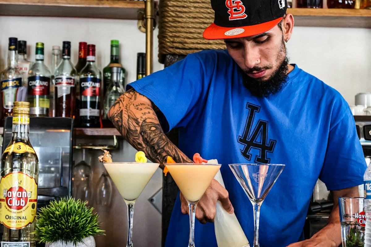 A bartender crafts cocktails behind a bar.