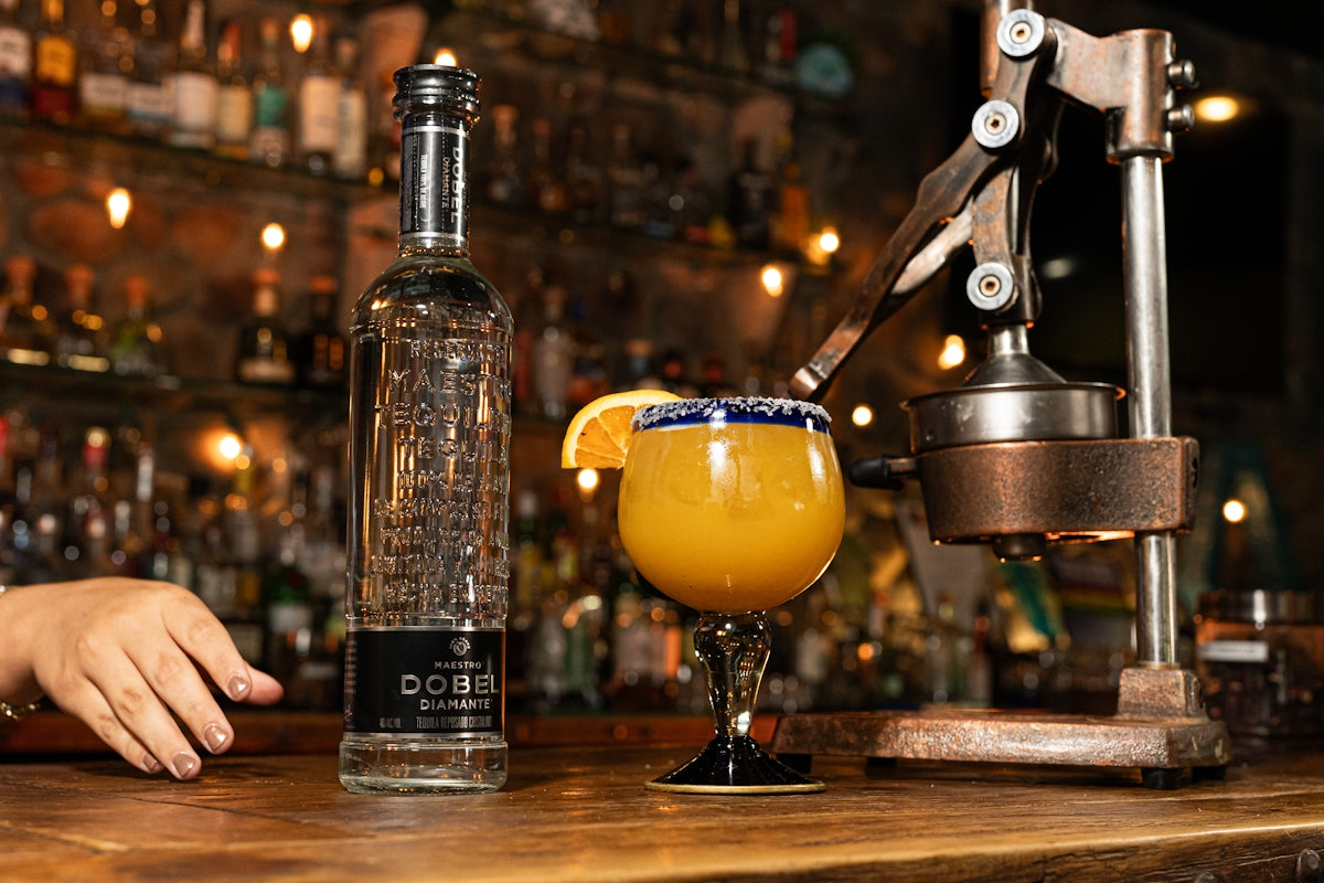 Bottle of tequila and orange cocktail at bar